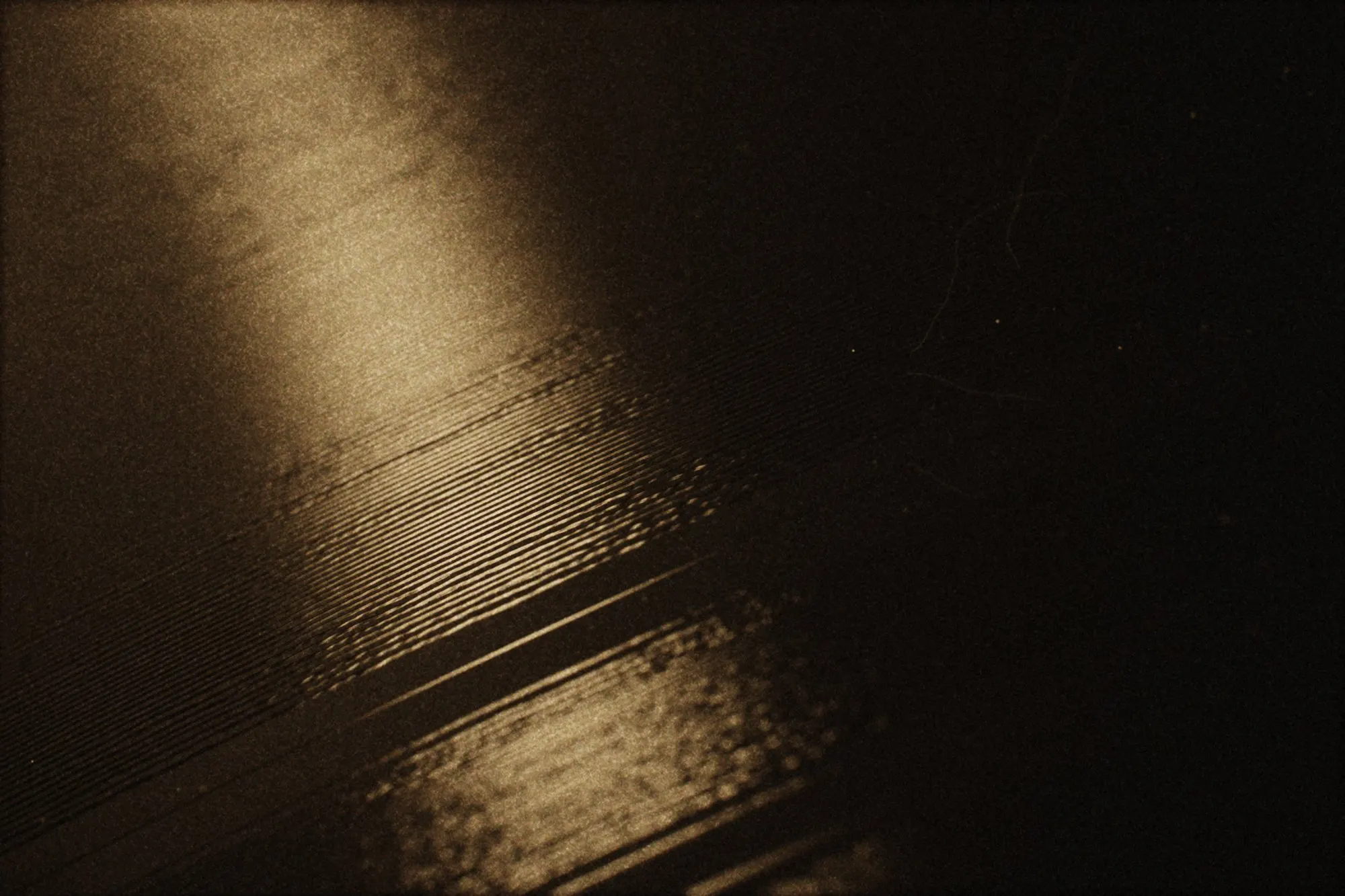 Macro de los surcos de un disco de vinilo con un reflejo de luz